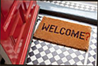 Welcome mat on a white and black checkered floor next to a red door